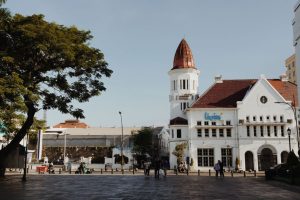 Ilustrasi proyek pembangunan rumah dengan latar belakang pemandangan kota di Jawa Timur, menggambarkan Biaya Bangun Rumah 2026 di Jawa Timur – Update Terbaru.